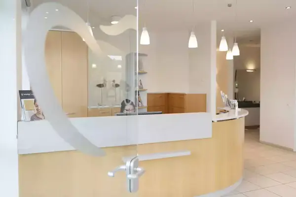 Moderne Zahnarztpraxis mit Empfangsbereich, freundlicher Atmosphäre und heller Einrichtung.