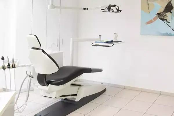 Moderner Zahnarztstuhl in heller Praxis mit zahnmedizinischem Equipment und Wandbild.